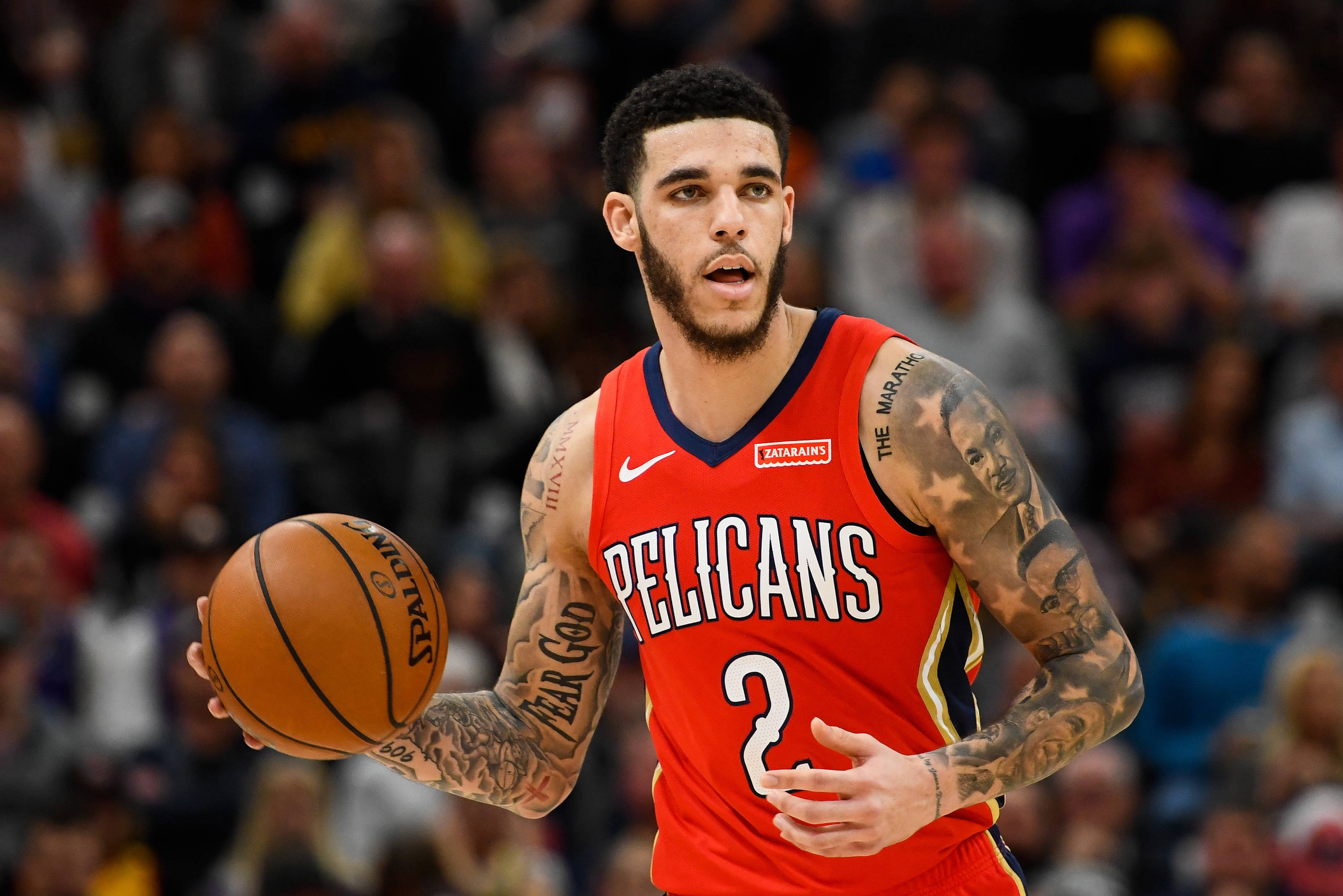 NBA 桌布 壁紙 — 一名身穿紅色Pelicans球衣的籃球運動員在比賽中運球，手臂上的刺青清晰可見。