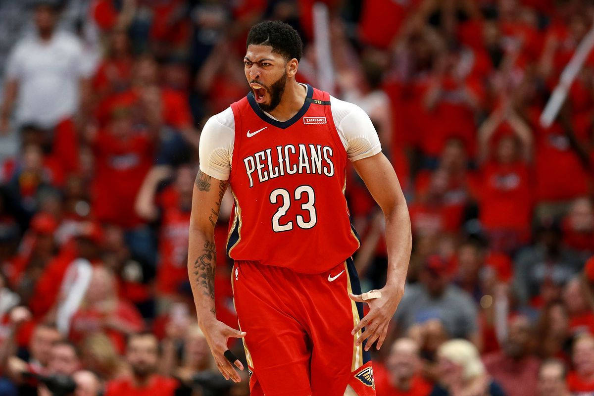 Anthony Davis 桌布 壁紙 — 一名身穿紅色Pelicans球衣23號的籃球運動員在比賽中激烈咆哮，身後是模糊的紅色人群。