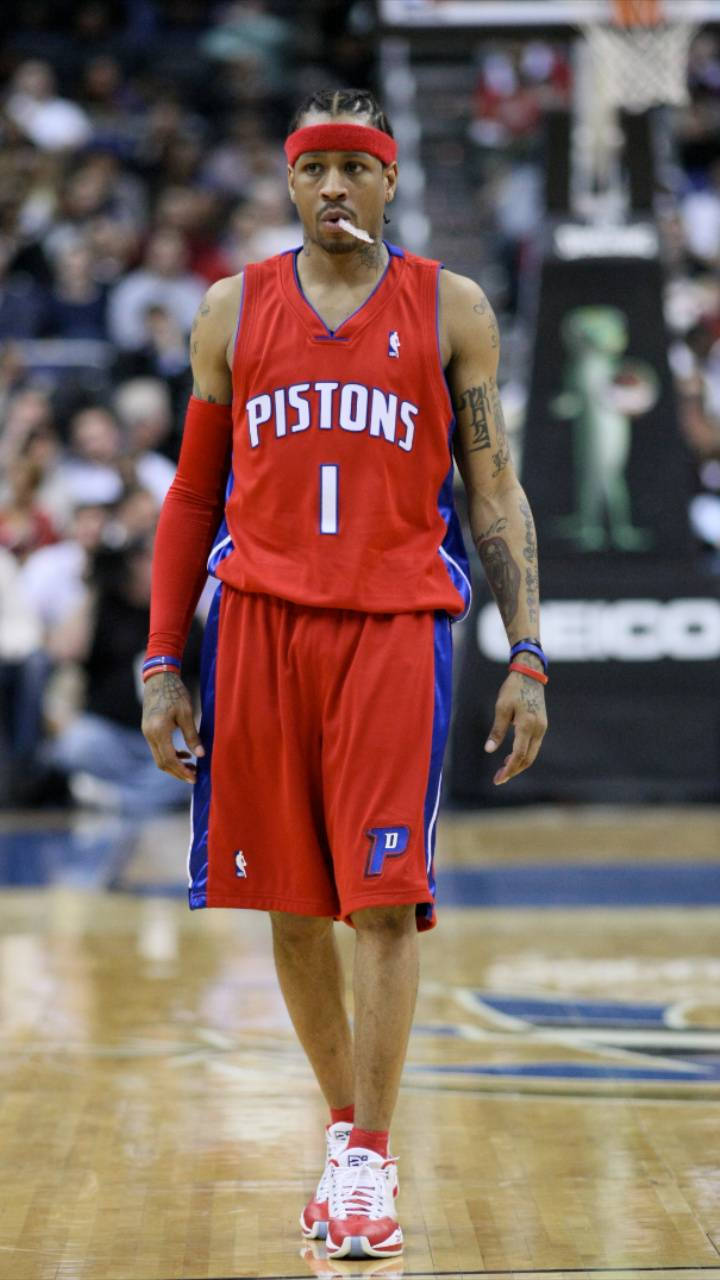 NBA iPhone 桌布 壁紙 — 一名身穿紅色Pistons球衣的籃球運動員在木地板上行走，手臂上的刺青清晰可見。