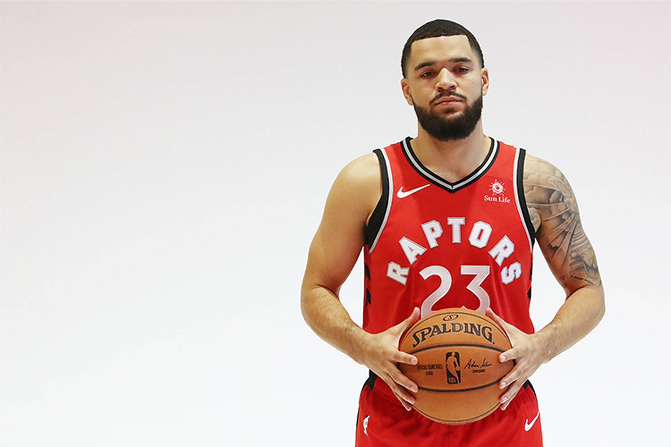 Fred Vanvleet 桌布 壁紙 — 一名身穿紅色Raptors球衣的籃球運動員，在純白色背景前手持Spalding籃球。