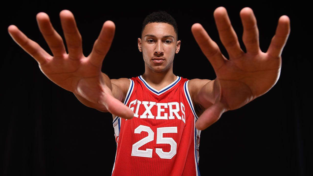 Ben Simmons 桌布 壁紙 — 一名身穿紅色Sixers球衣、號碼25的籃球運動員在黑色背景前伸出雙手。