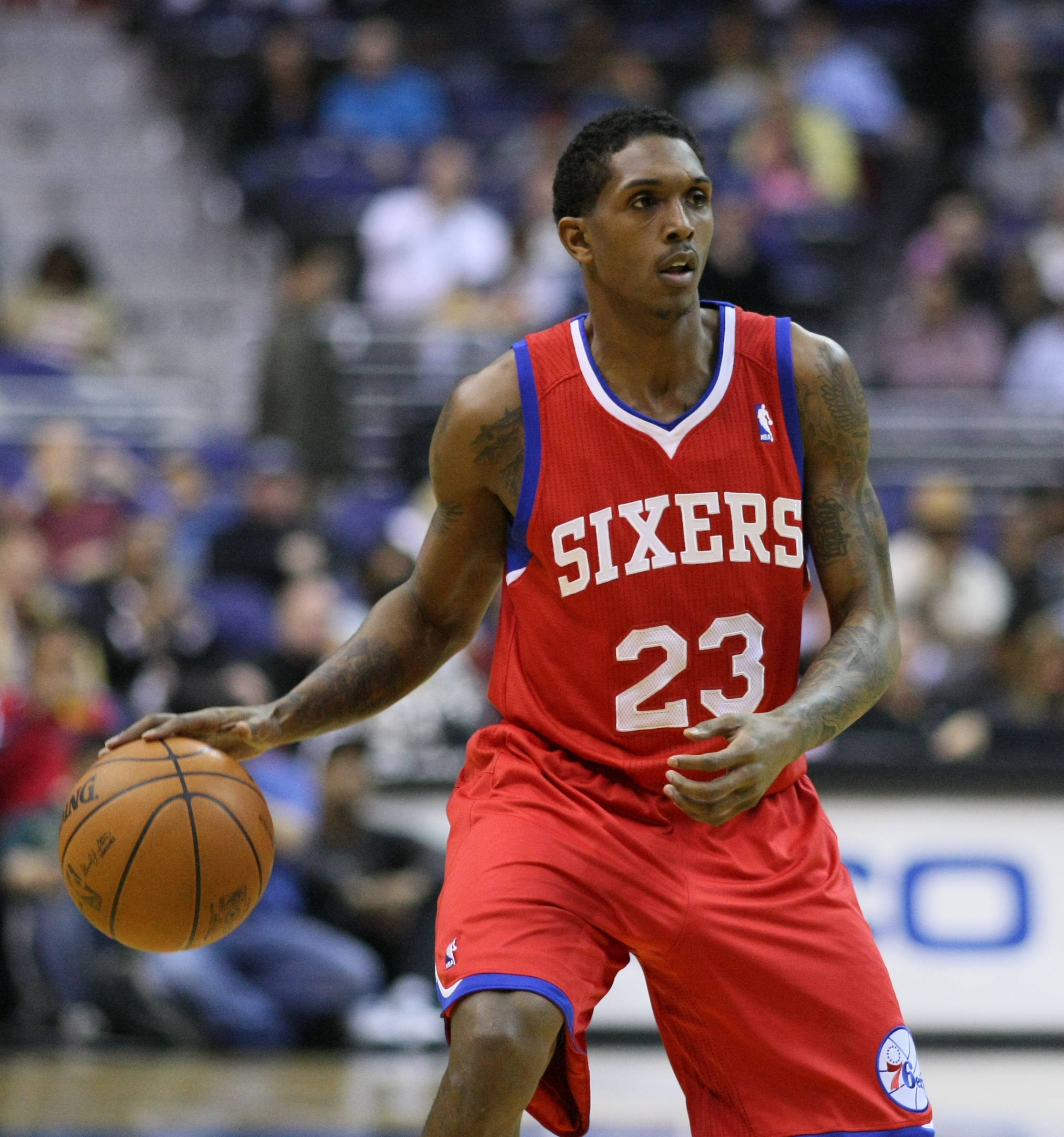 Lou Williams 桌布 壁紙 — 一名身穿紅色Sixers球衣的籃球運動員在明亮的場館燈光下，於激烈的比賽中運球。