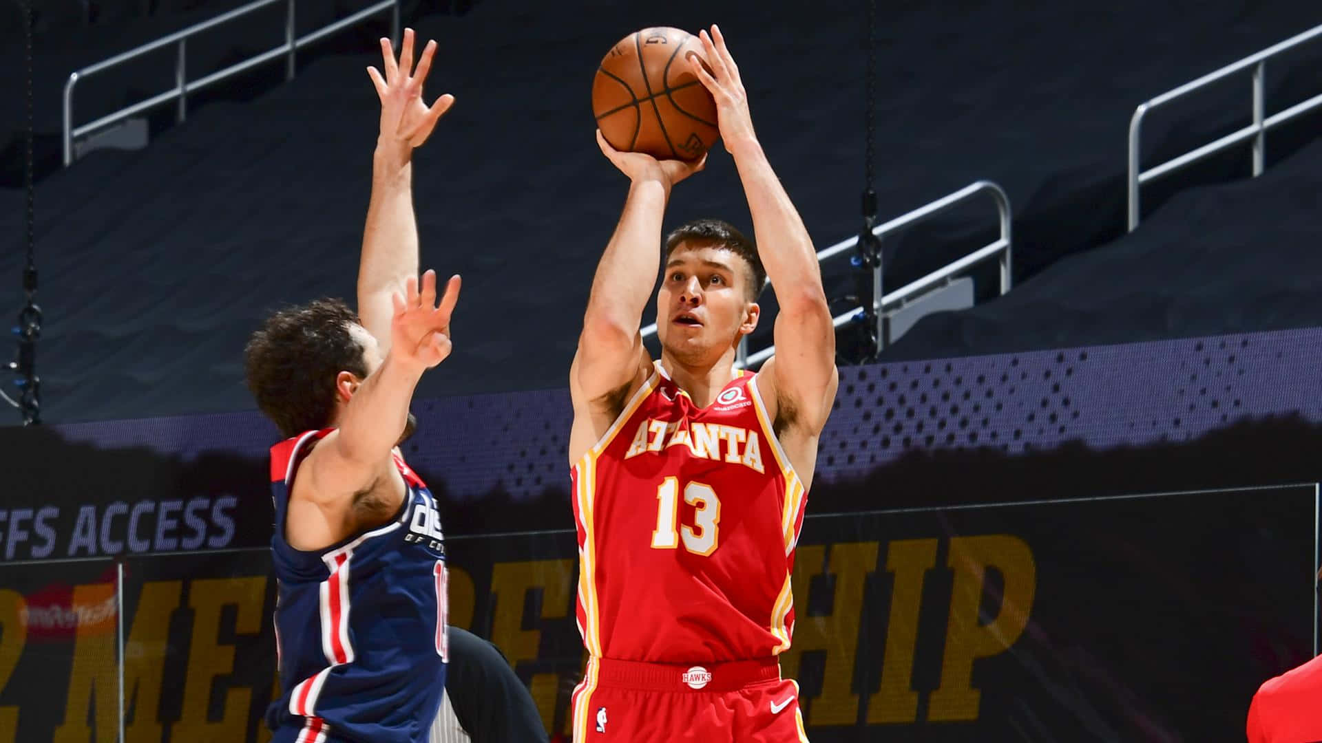 NBA 桌布 壁紙 — 一名身穿紅色亞特蘭大球衣的籃球運動員跳投，而一名藍色防守球員舉手阻擋。