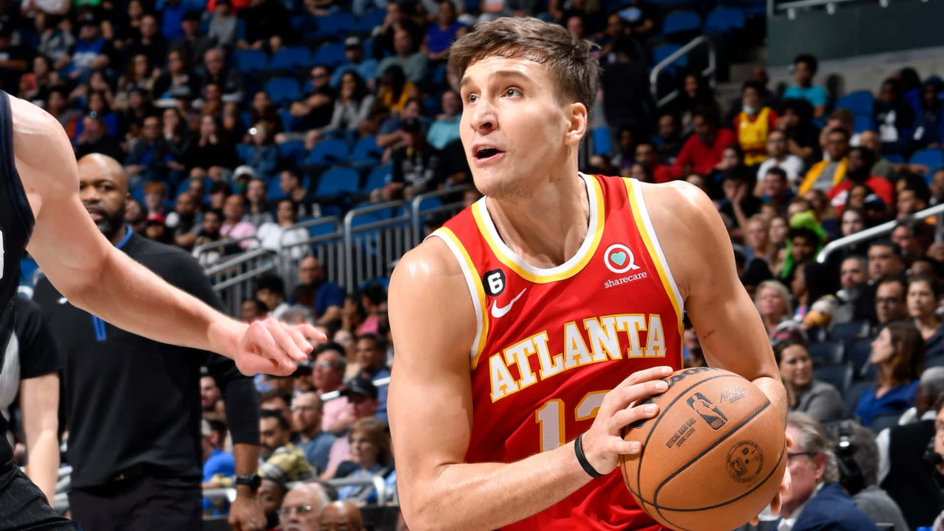 NBA 桌布 壁紙 — 一名身穿紅色亞特蘭大球衣的籃球運動員在擠滿觀眾的場館中運球，同時被防守。