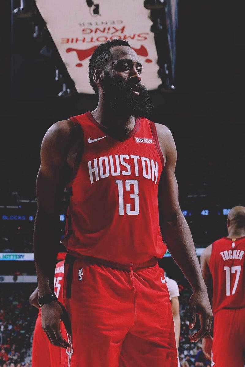 James Harden 桌布 壁紙 — 一名身穿紅色休士頓火箭隊球衣的籃球運動員在場館燈光下專注地站在球場上。