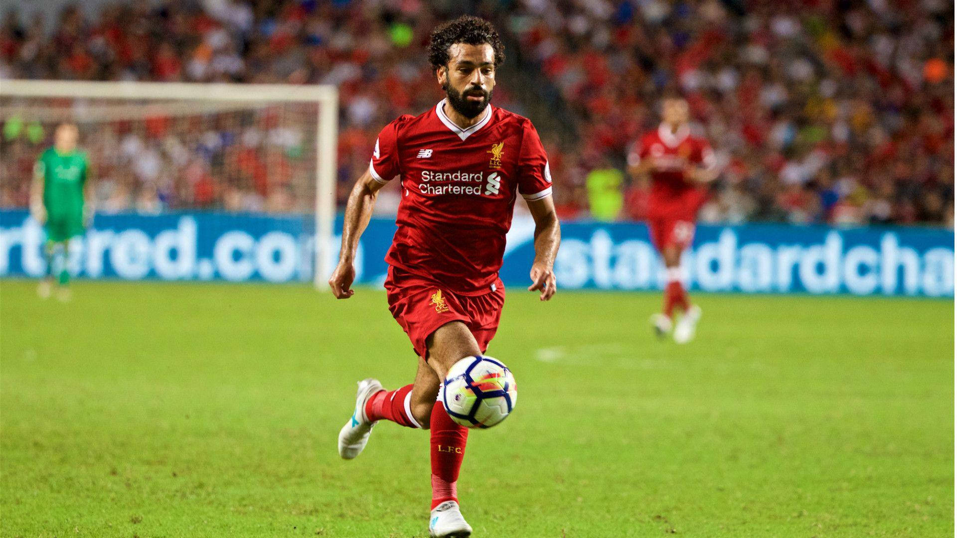 Salah 桌布 壁紙 — 一名身穿紅色利物浦球衣的足球員在球場燈光下於充滿活力的綠色草地上盤球。