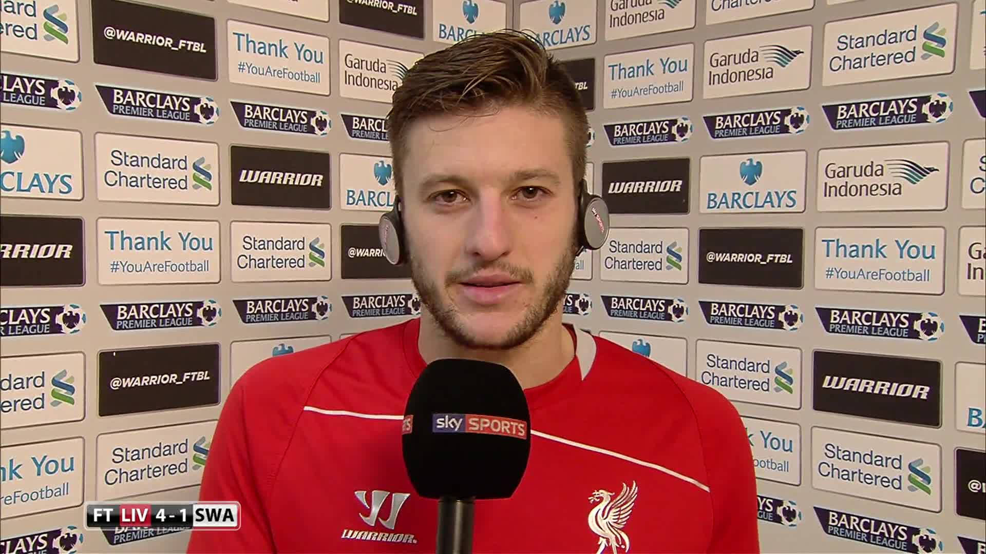 Liverpool Fc 桌布 壁紙 — 一名身穿紅色利物浦球衣的足球員在品牌背景板前對著Sky Sports麥克風講話。