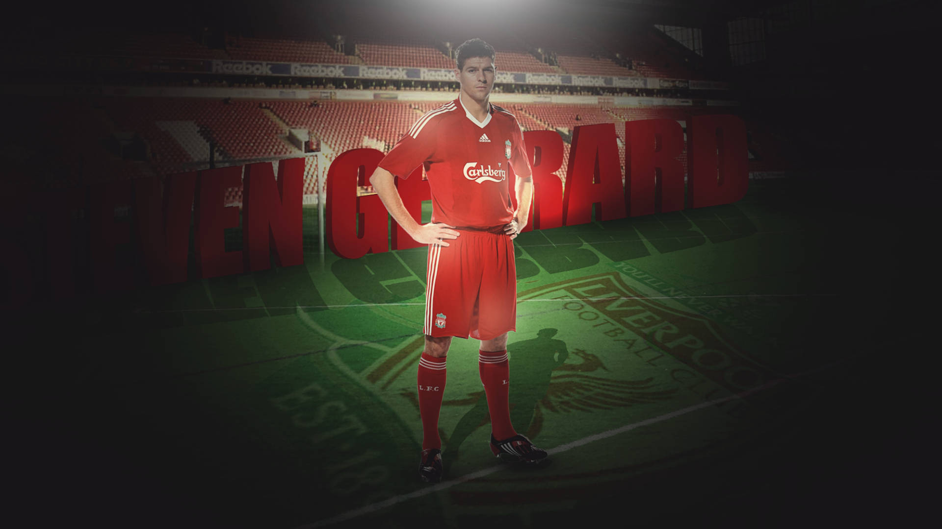Steven Gerrard 桌布 壁紙 — 一名身穿紅色利物浦球衣的足球員自信地站在球場上，身後是體育館座位和巨型字母，在戲劇性的聚光燈下。