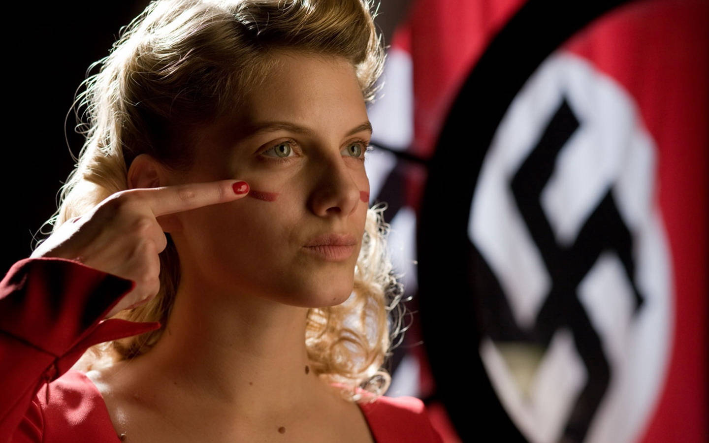 Inglourious Basterds 桌布 壁紙 — 一名身穿紅色制服的女人指向自己的臉頰，背後有模糊的卐字旗。