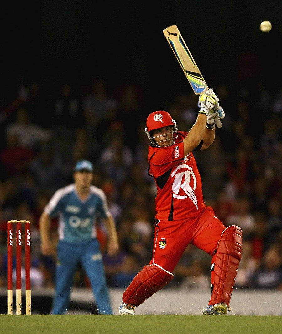 Aaron Finch 桌布 壁紙 — 一名身穿紅色制服的板球擊球手在夜間比賽中，在體育場燈光下揮動球棒擊球。