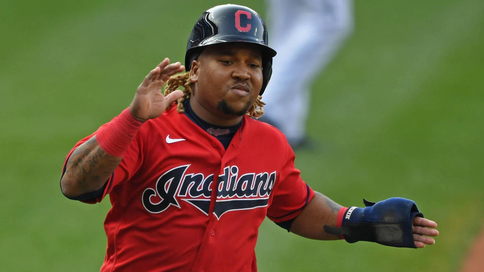 Jose Ramirez 桌布 壁紙 — 一名身穿紅色印第安人球衣的棒球運動員在綠色場地上奔跑時向球迷揮手。