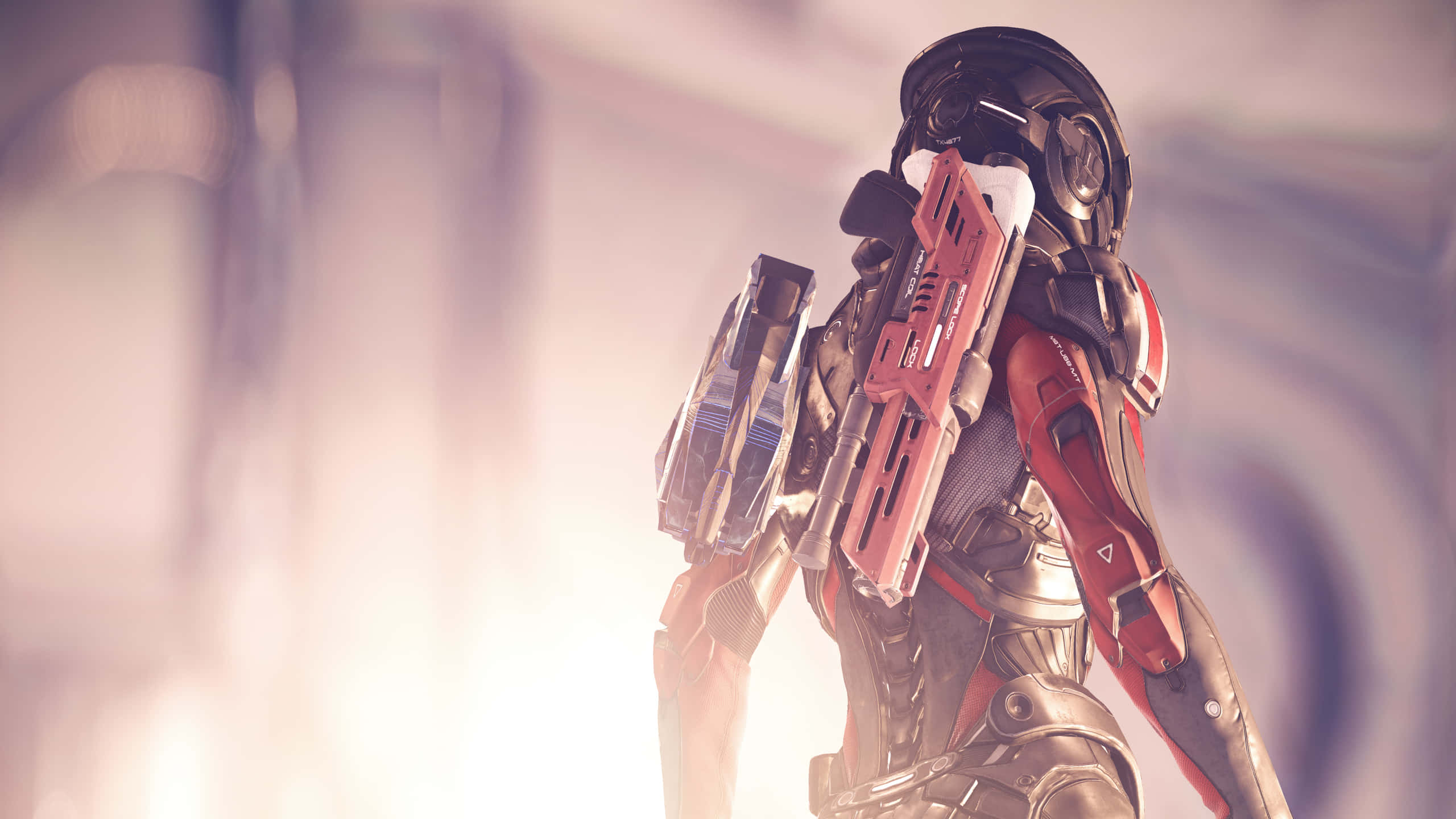 Mass Effect Andromeda 桌布 壁紙 — 一名身穿紅色和黑色盔甲的未來士兵站在朦朧發光的環境中手持武器。