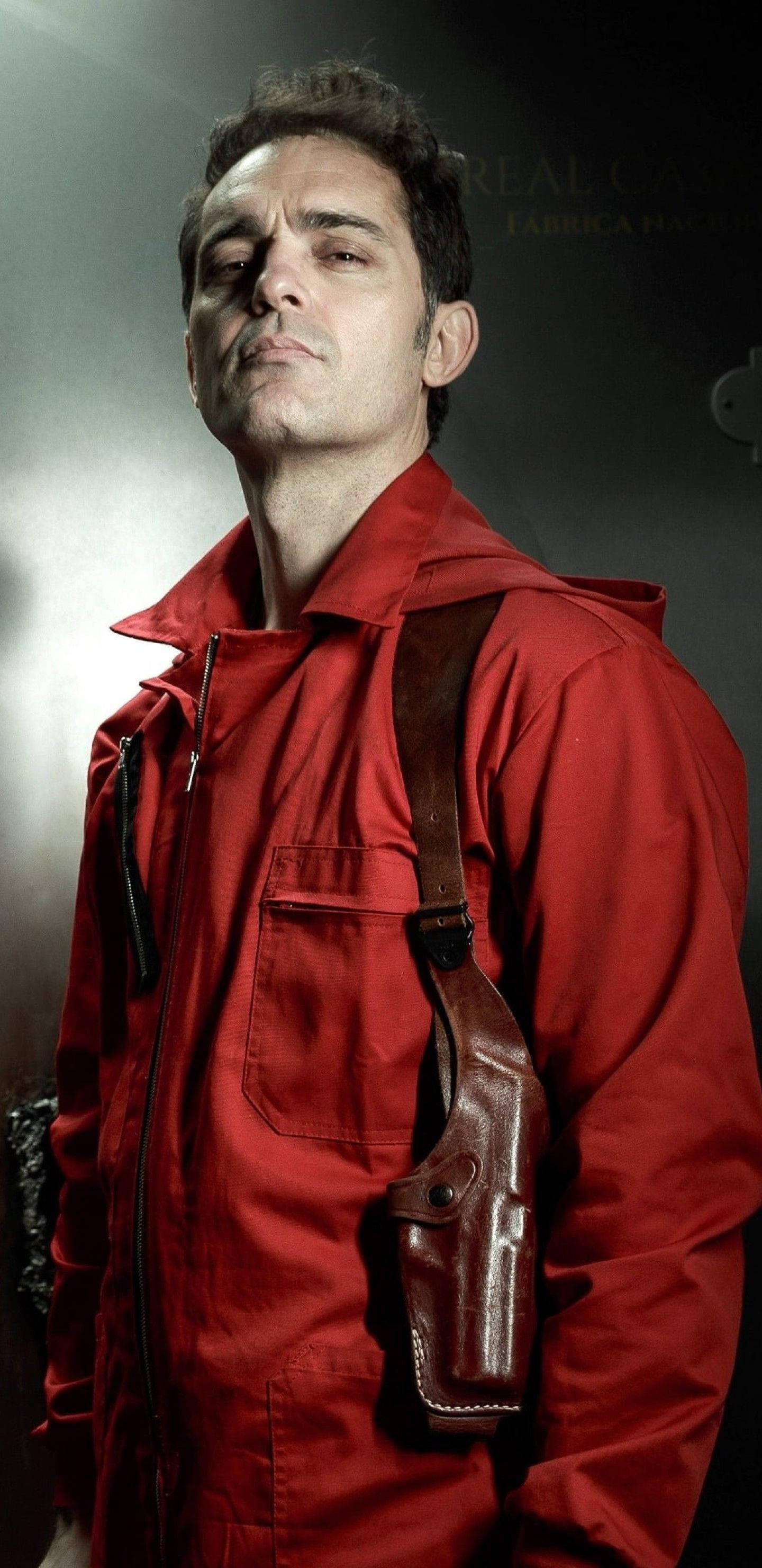 Berlin Money Heist 桌布 壁紙 — 一名身穿紅色外套、腰間槍套內有手槍的男子站在戲劇性的攝影棚燈光下。