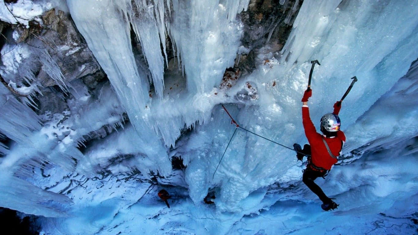 Ice Climbing 桌布 壁紙 — 一名身穿紅色外套的攀冰者，正用冰斧和繩索攀登高聳的冰凍瀑布。