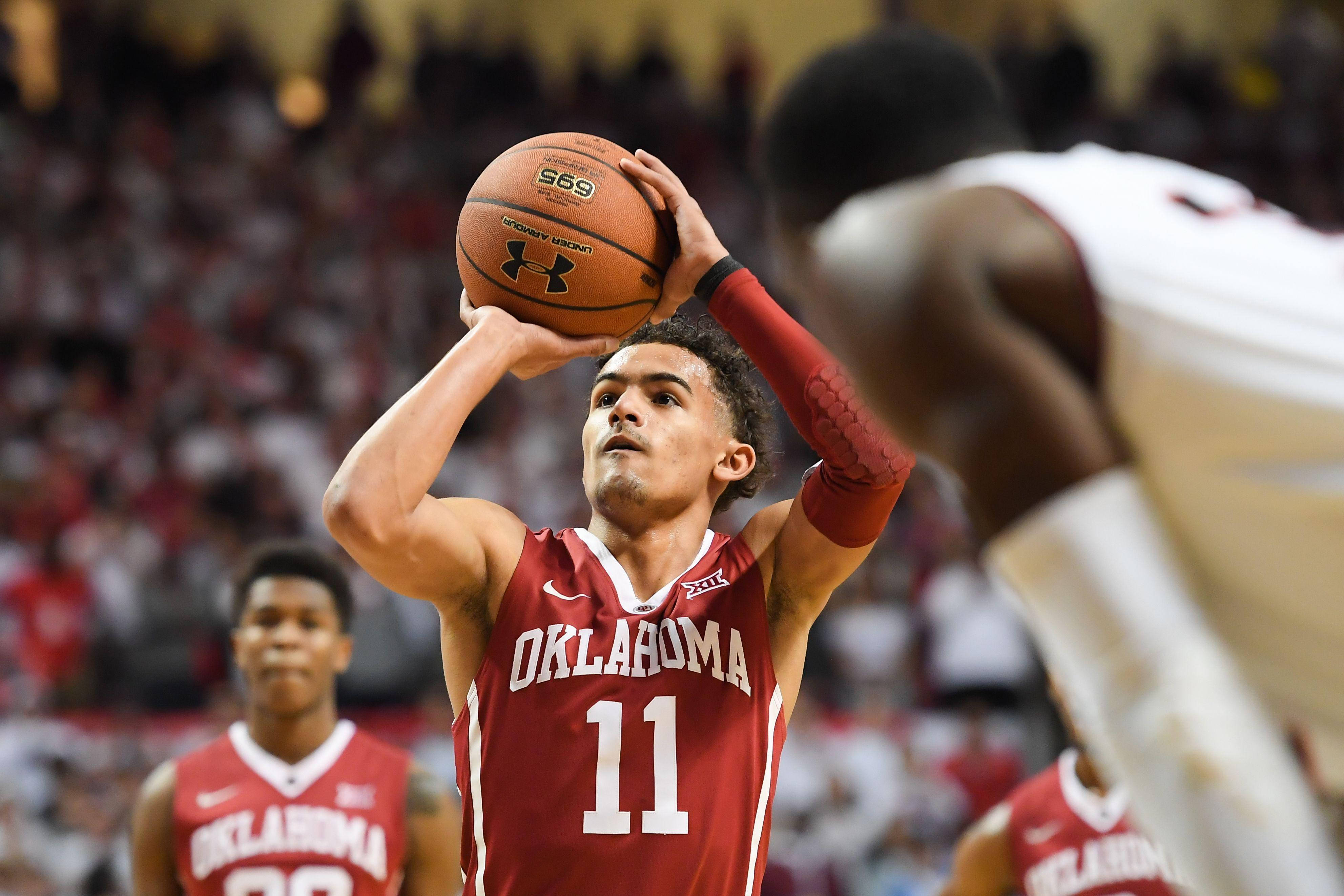 Trae Young 桌布 壁紙 — 一名身穿紅色奧克拉荷馬球衣的籃球運動員在比賽中專注地投出跳投。