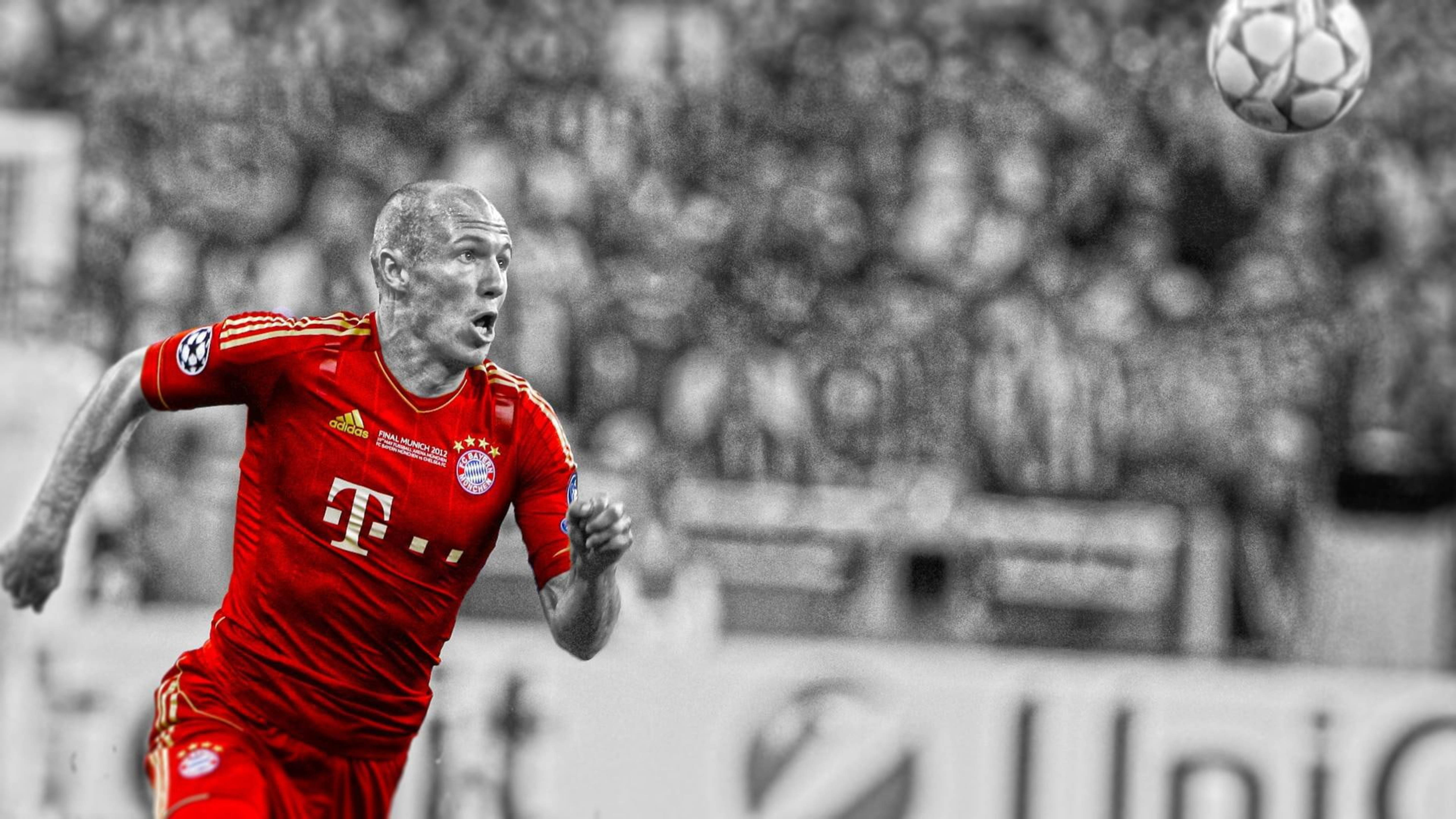 Bayern 桌布 壁紙 — 一名身穿紅色拜仁慕尼黑球衣的足球員跳起頭球，背景是模糊的黑白球場人群。