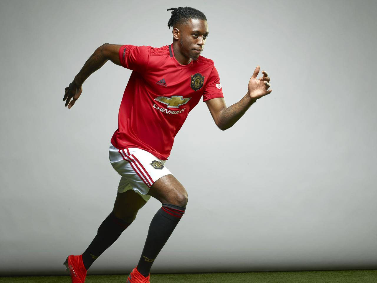 Football Players 桌布 壁紙 — 一名身穿紅色曼聯球衣的足球員在純灰色工作室背景下動態衝刺。