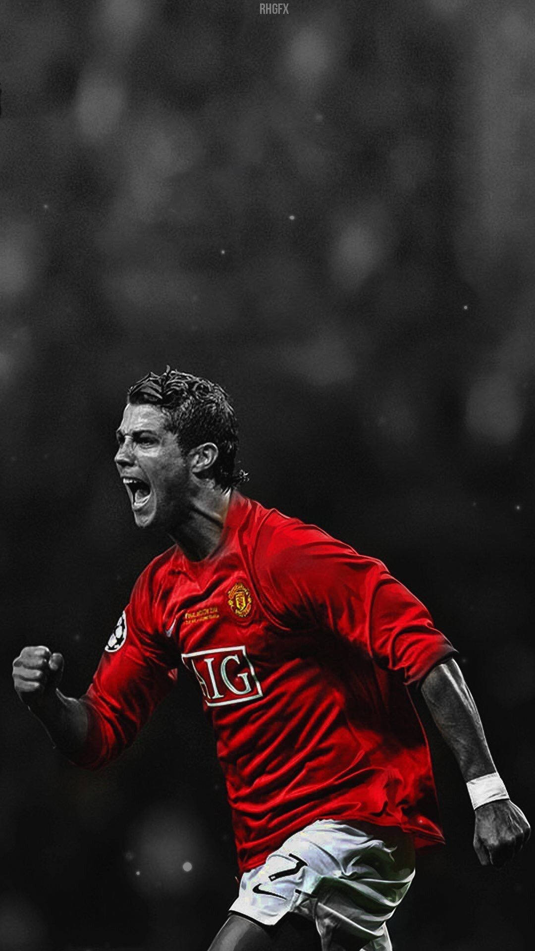 Ronaldo 桌布 壁紙 — 一名身穿紅色曼聯球衣的足球運動員，在模糊的球場背景下握緊拳頭，發出勝利的咆哮。