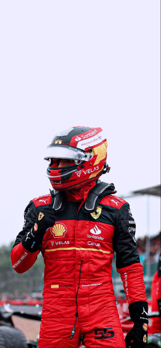 Racing 桌布 壁紙 — 一名身穿紅色法拉利賽車服和頭盔的F1車手自信地站在賽道旁，贊助商標誌清晰可見。