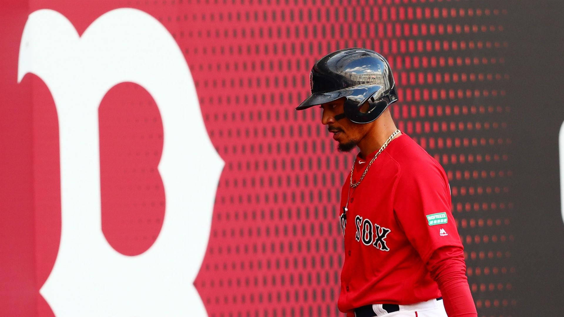 Mookie Betts 桌布 壁紙 — 一名身穿紅色波士頓紅襪隊球衣的棒球運動員走過一面帶有白色 'B' 標誌的紅色大牆。