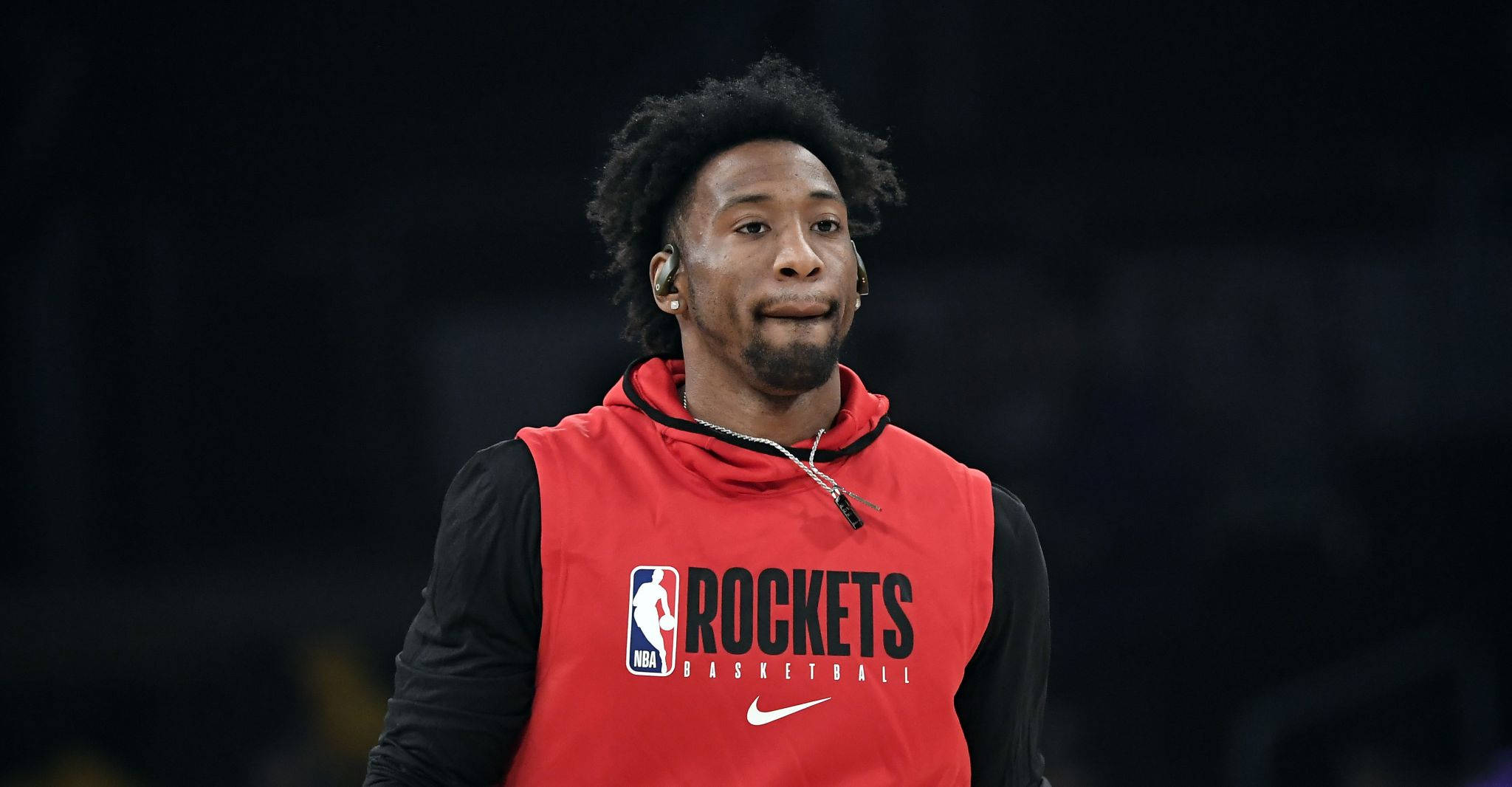 robert covington 桌布 壁紙 — 一名身穿紅色火箭訓練背心的籃球運動員在場館燈光下抬頭仰望，神情專注。