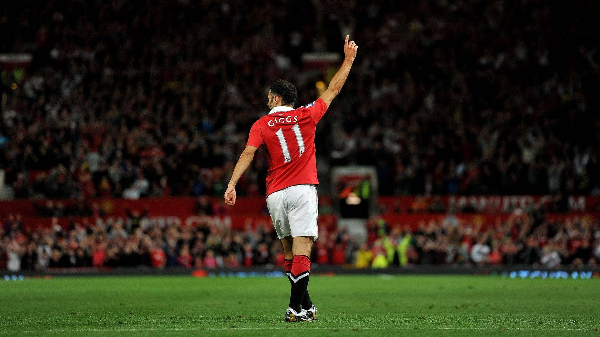 Ryan Giggs 桌布 壁紙 — 一名身穿紅色球衣、背號11的足球運動員在夜間燈光明亮的球場上向球迷揮手。