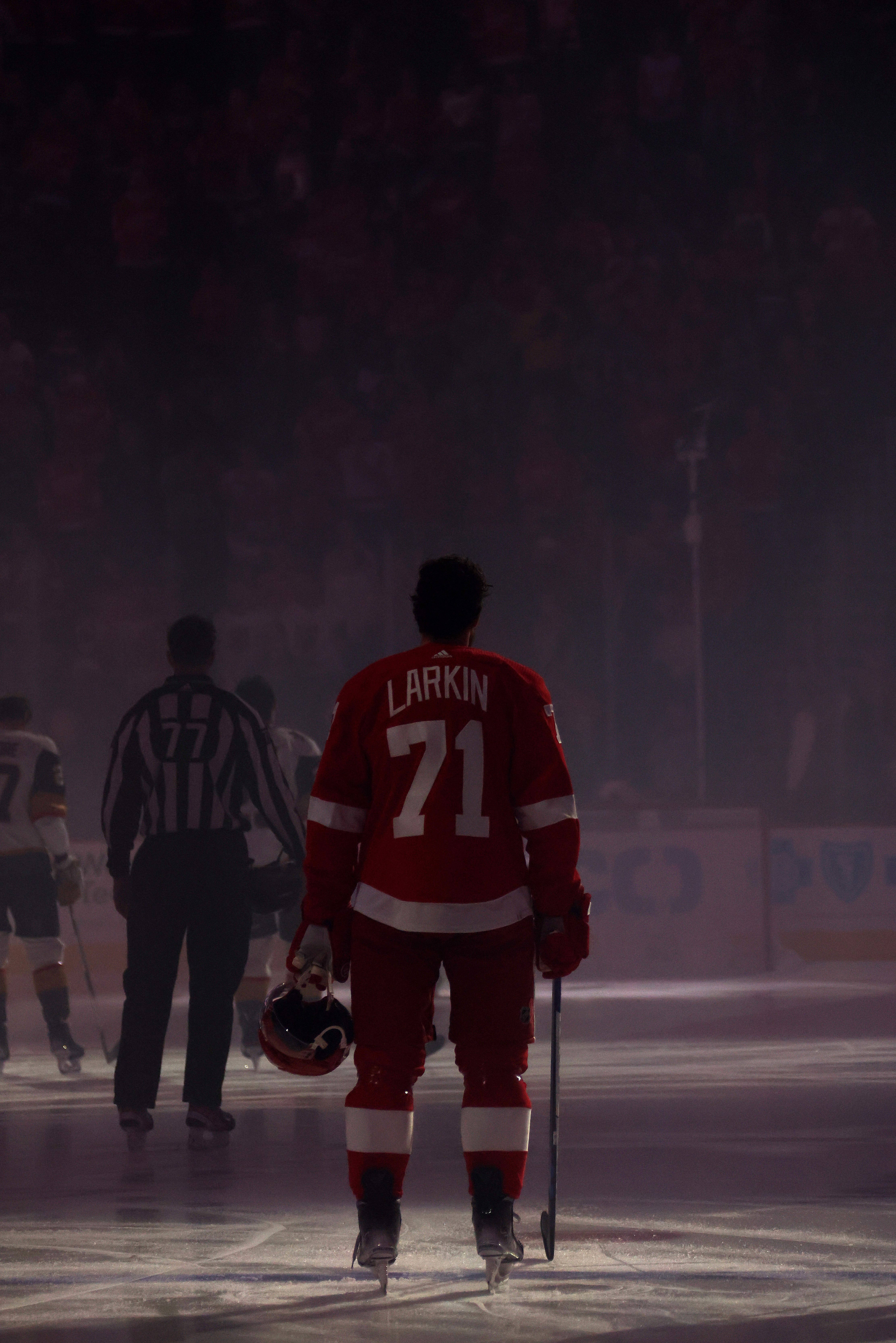 hockey 桌布 壁紙 — 一名身穿紅色球衣、背號71的冰球運動員在競技場燈光下的冰面上遠離鏡頭，背景有模糊的觀眾。