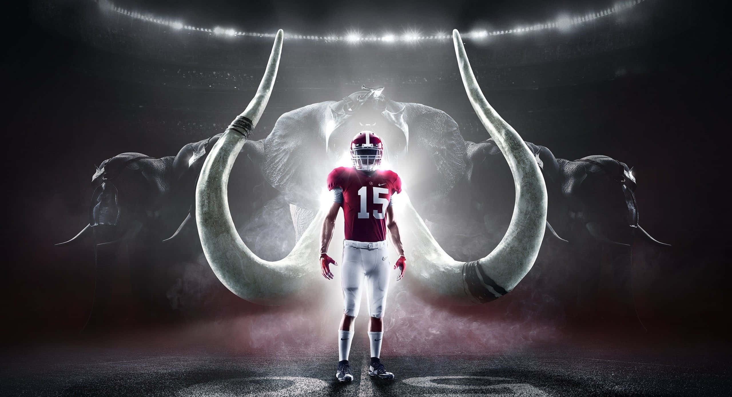 Alabama Football 桌布 壁紙 — 一名身穿紅色球衣15號的足球員站在黑暗的體育場中，面前是一隻發光且擁有巨大象牙的大象。