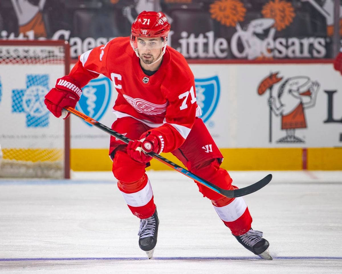 hockey 桌布 壁紙 — 一名身穿紅色球衣的冰球運動員在比賽中專注地、充滿決心地在冰上激烈滑行。