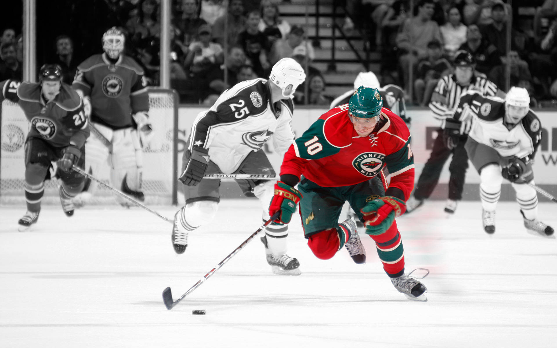 hockey 桌布 壁紙 — 一名身穿紅色球衣的冰球運動員爭奪冰球，對手和裁判在冰上專注觀看。