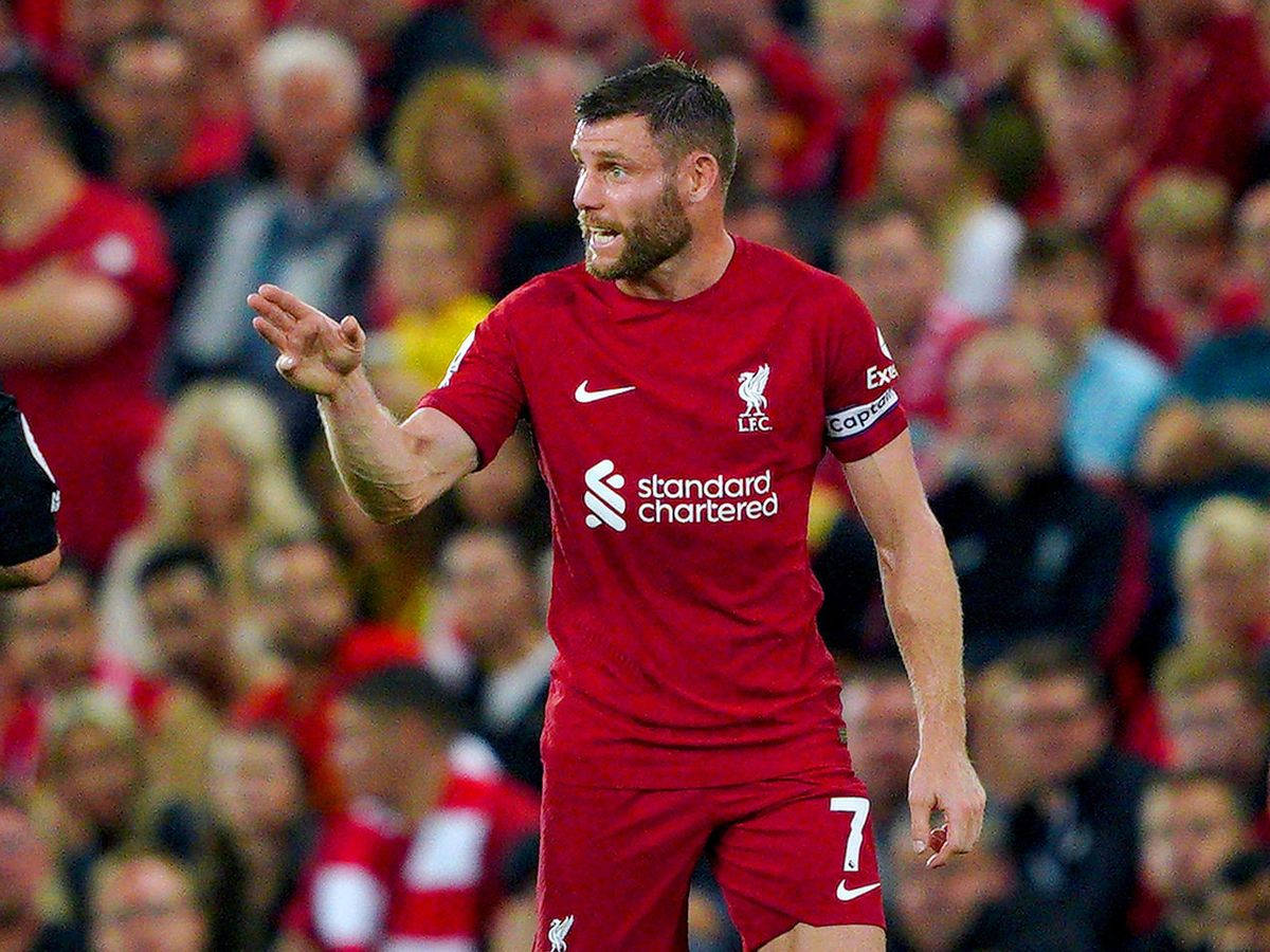 Liverpool Fc 桌布 壁紙 — 一名身穿紅色球衣的利物浦足球員在模糊的人群前，於比賽中熱情地做手勢。
