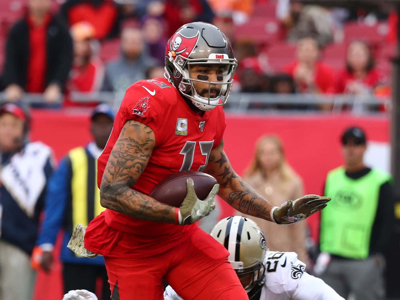 Mike Evans 桌布 壁紙 — 一名身穿紅色球衣的坦帕灣海盜隊美式足球員在比賽中持球奔跑，背景有球迷。