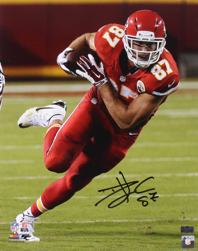 Travis Kelce 桌布 壁紙 — 一名身穿紅色球衣的堪薩斯城酋長隊美式足球員在夜間比賽中，於燈光球場上持球衝刺。