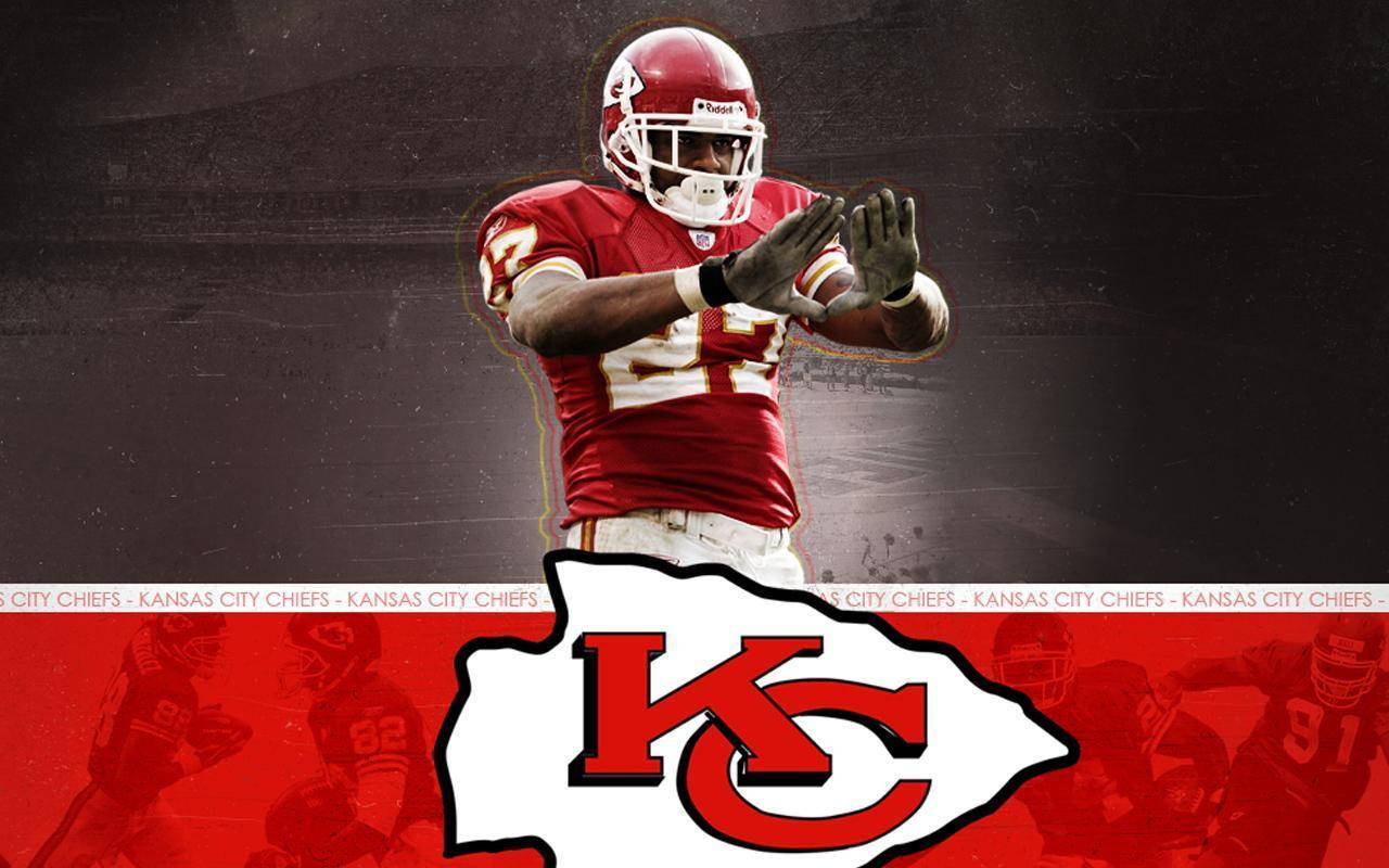 Kc Chiefs 桌布 壁紙 — 一名身穿紅色球衣的堪薩斯城酋長隊美式足球員在帶有球隊標誌和球員剪影的深色紋理背景上拍手。