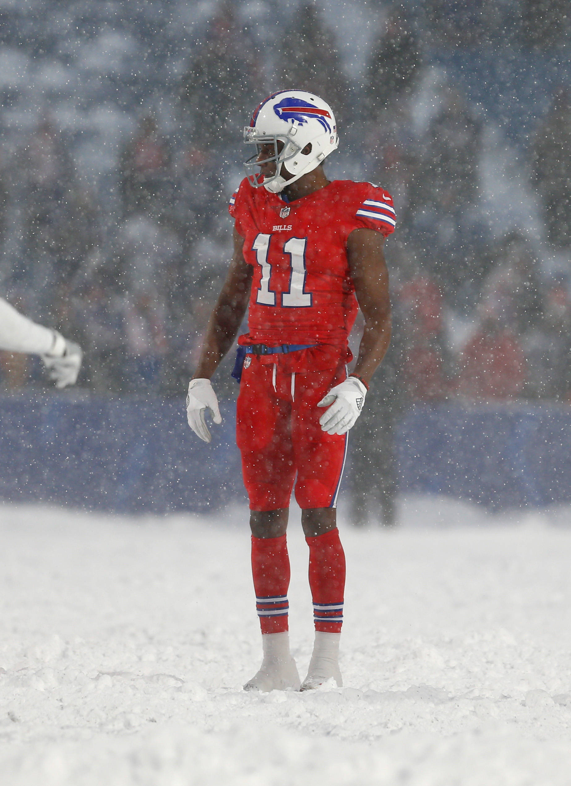 zay jones 桌布 壁紙 — 一名身穿紅色球衣的布法羅比爾隊美式足球員獨自站在積雪的球場上，雪花在他周圍飄落。