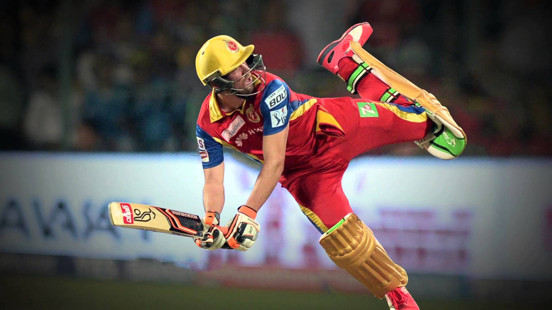 royal challengers bangalore 桌布 壁紙 — 一名身穿紅色球衣的板球運動員在夜間比賽中，在球場燈光下，手持球棒和頭盔，在揮桿中途動態跳躍。
