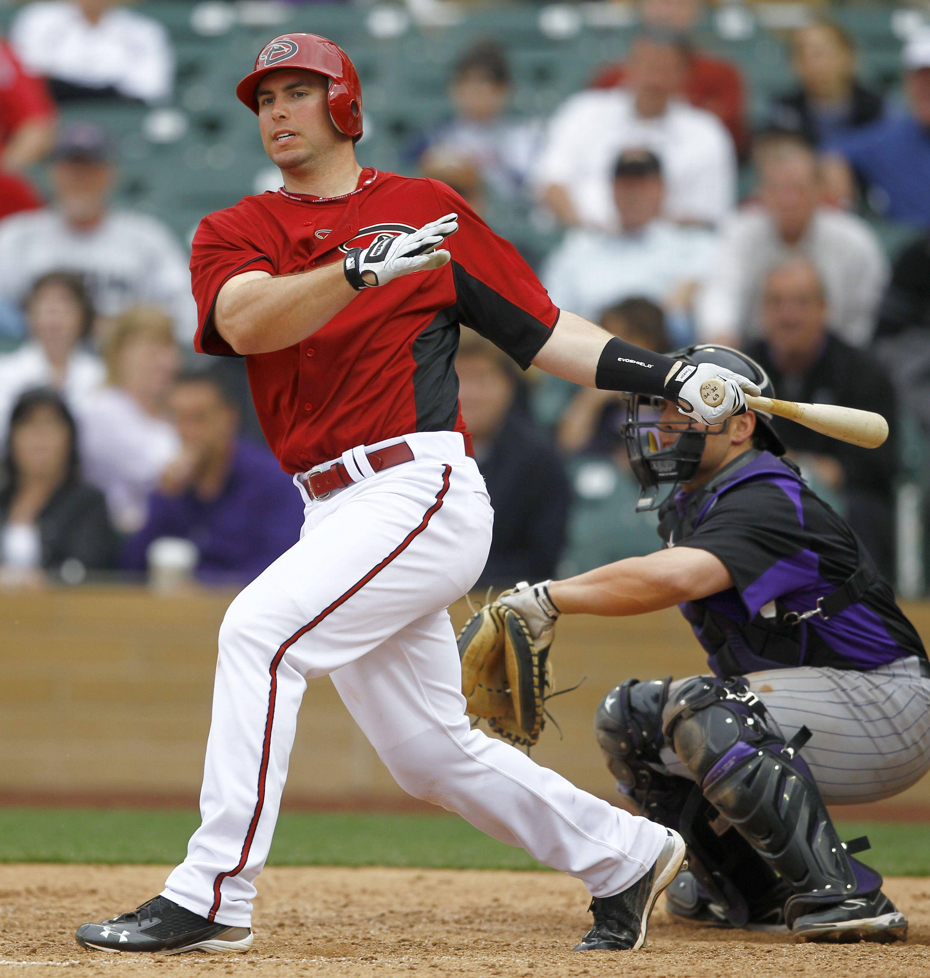 Paul Goldschmidt 桌布 壁紙 — 一名身穿紅色球衣的棒球打擊手揮棒擊球，捕手蹲在他身後，體育場內坐滿觀眾。