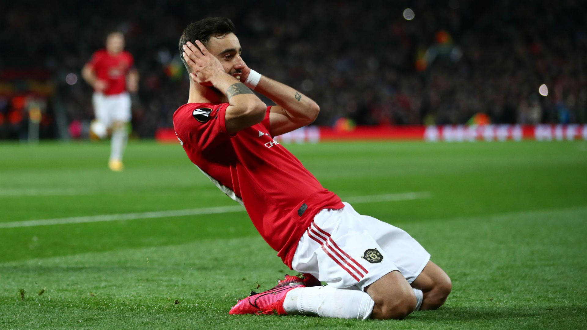 曼聯 桌布 壁紙 — 一名身穿紅色球衣的足球員在夜間比賽中情緒激動，跪在草地上雙手掩面。