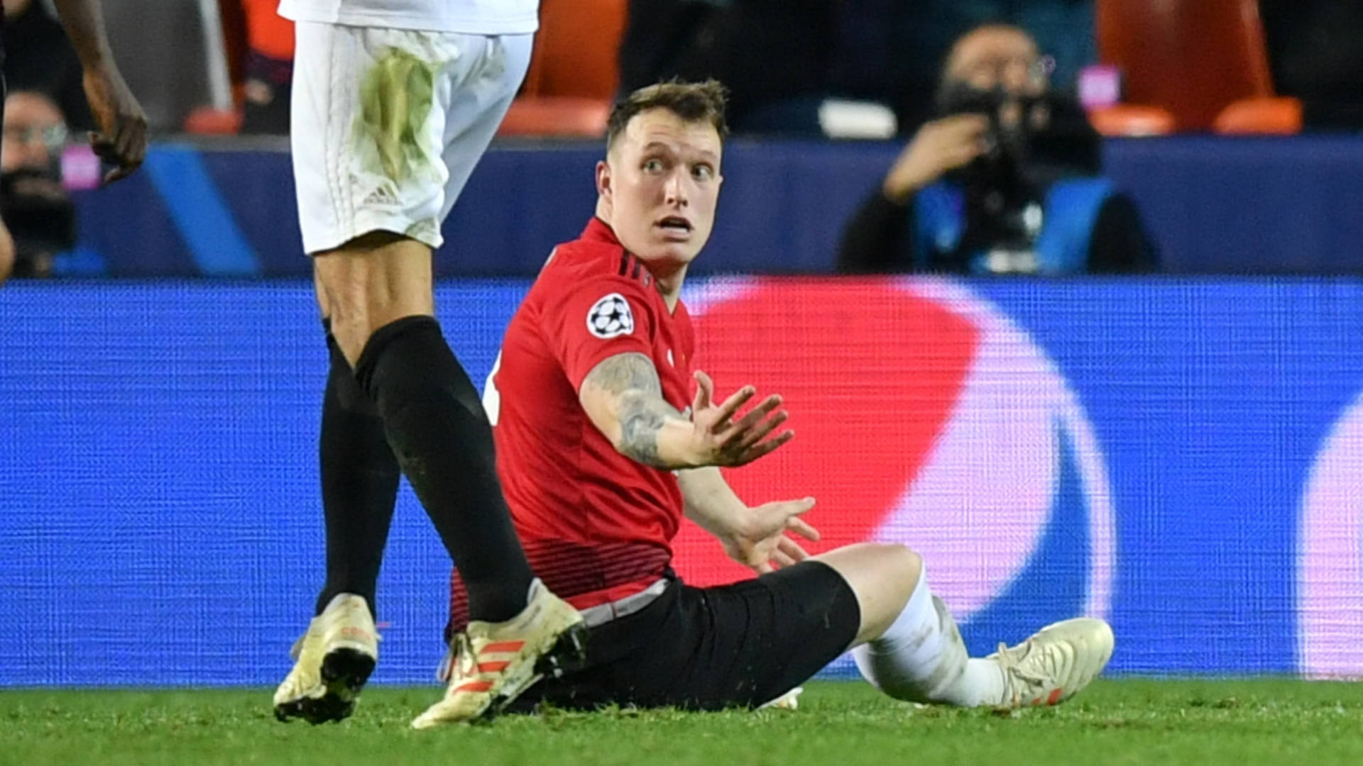 Champions League 桌布 壁紙 — 一名身穿紅色球衣的足球員在鏟球後呆坐在草地上，難以置信地伸出雙手。