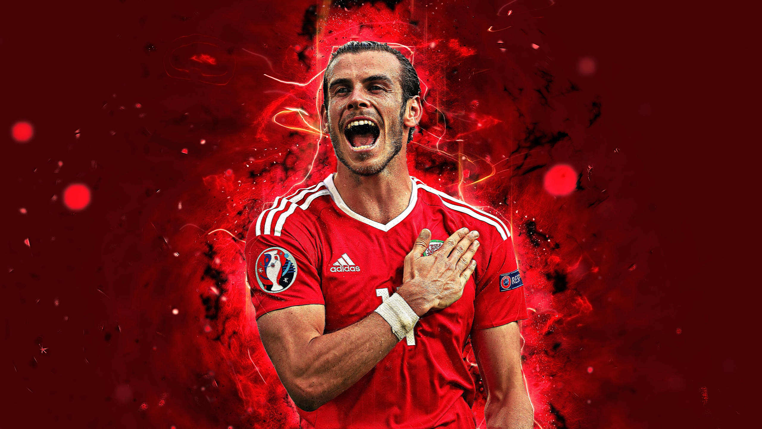 Gareth Bale 桌布 壁紙 — 一名身穿紅色球衣的足球運動員，在火紅的抽象背景前，熱情地將一隻手放在胸前慶祝。