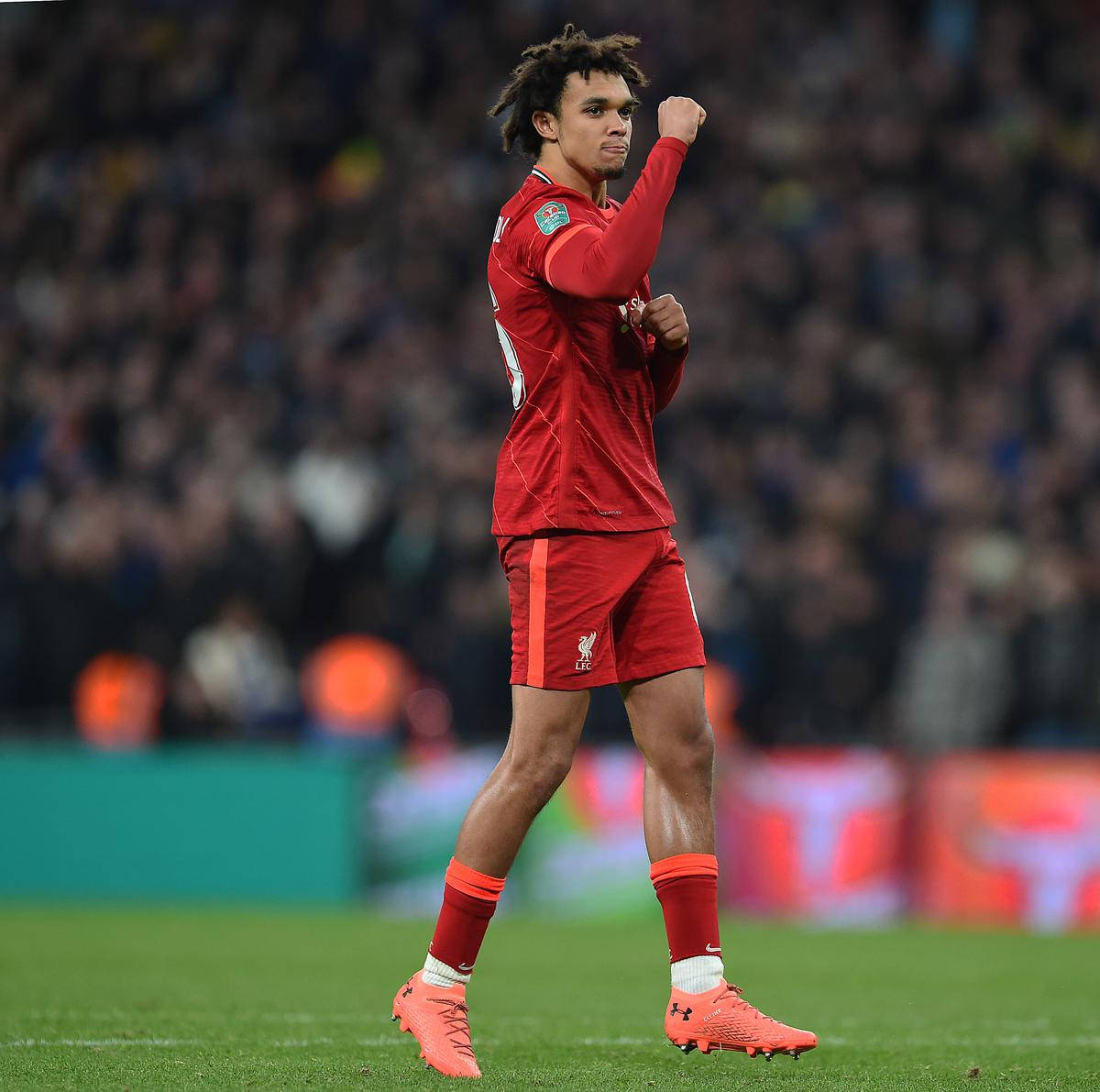 fist pump 桌布 壁紙 — 一名身穿紅色球衣的足球運動員在明亮燈光下的球場上舉起拳頭慶祝。