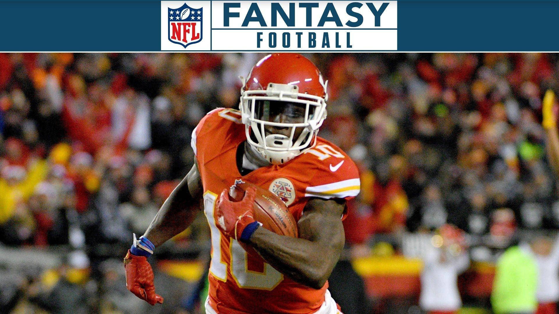 Tyreek Hill 桌布 壁紙 — 一名身穿紅色球衣的足球運動員在比賽中，在球場燈光下帶球奔跑，背景是模糊的球迷。