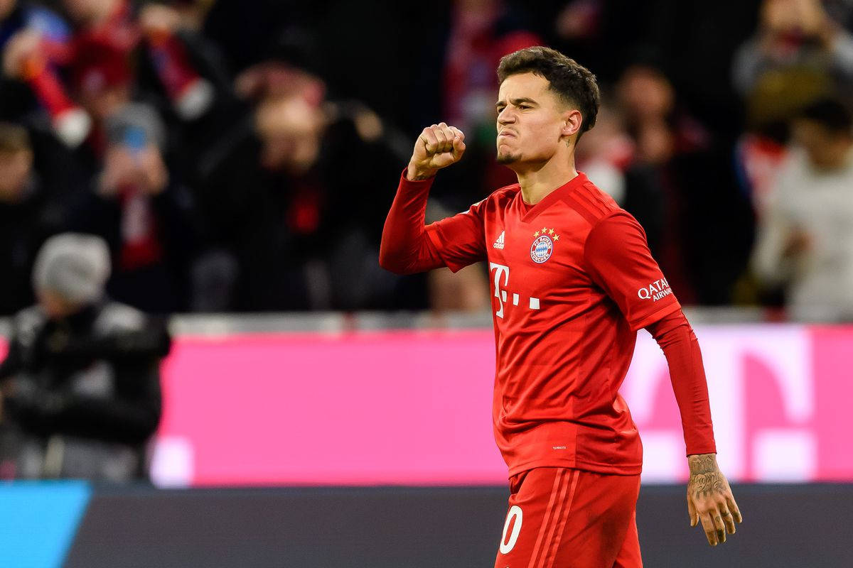 Coutinho 桌布 壁紙 — 一名身穿紅色球衣的足球運動員在燈火通明的球場上握拳慶祝勝利。