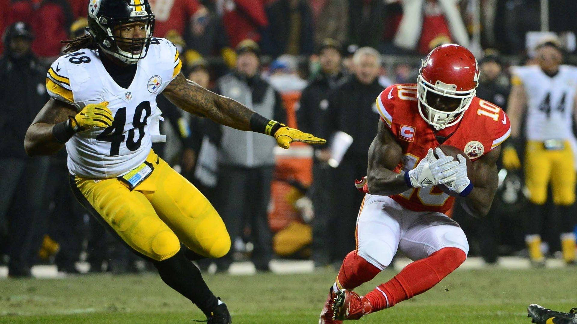 Tyreek Hill 桌布 壁紙 — 一名身穿紅色的堪薩斯城酋長隊球員帶著球奔跑，而身穿黃色的匹茲堡鋼人隊防守球員在夜間比賽中逼近。