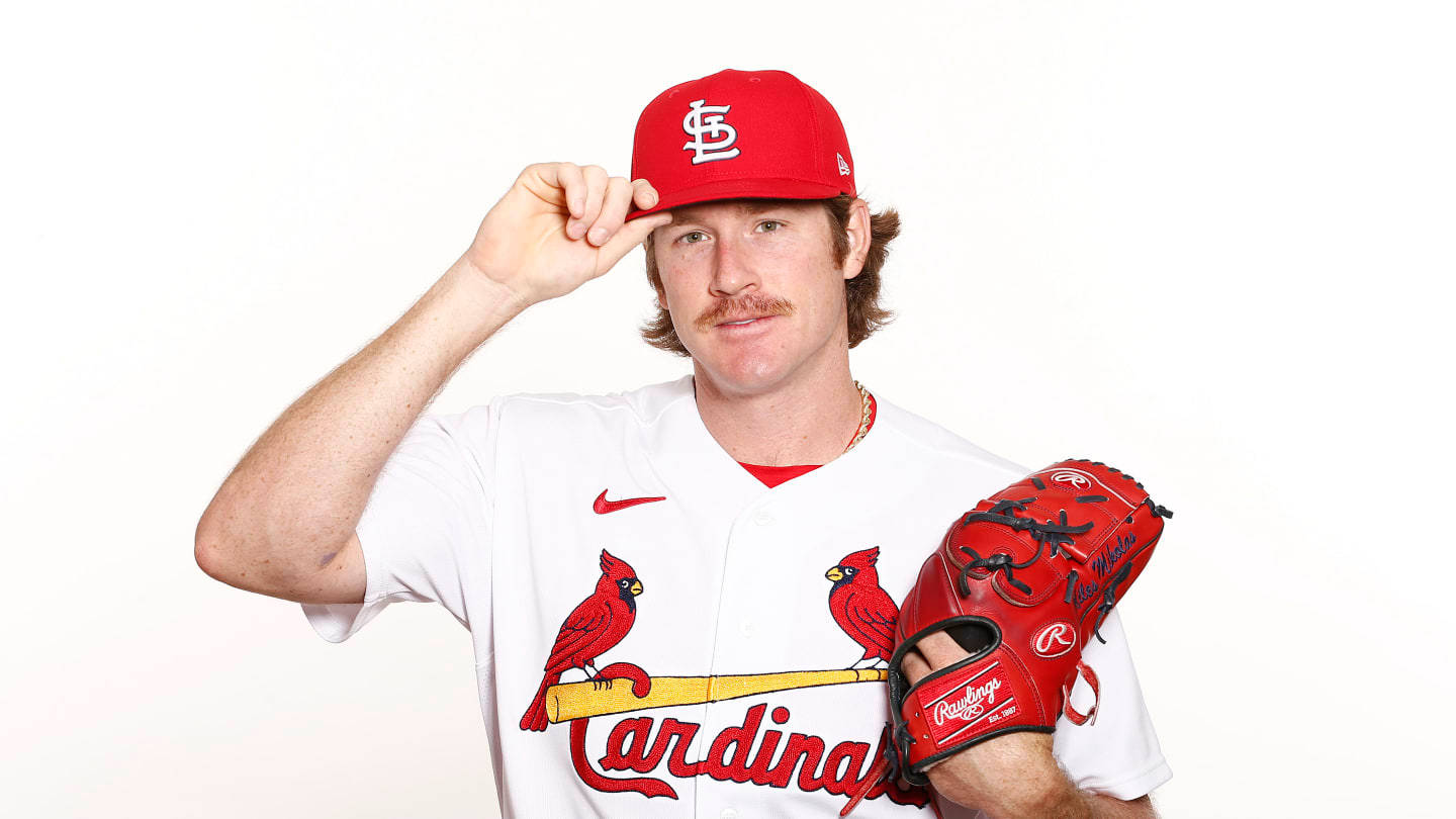 St Louis Cardinals 桌布 壁紙 — 一名身穿紅色紅雀隊帽子和白色球衣的棒球運動員，在純白色背景前手持紅色手套敬禮。