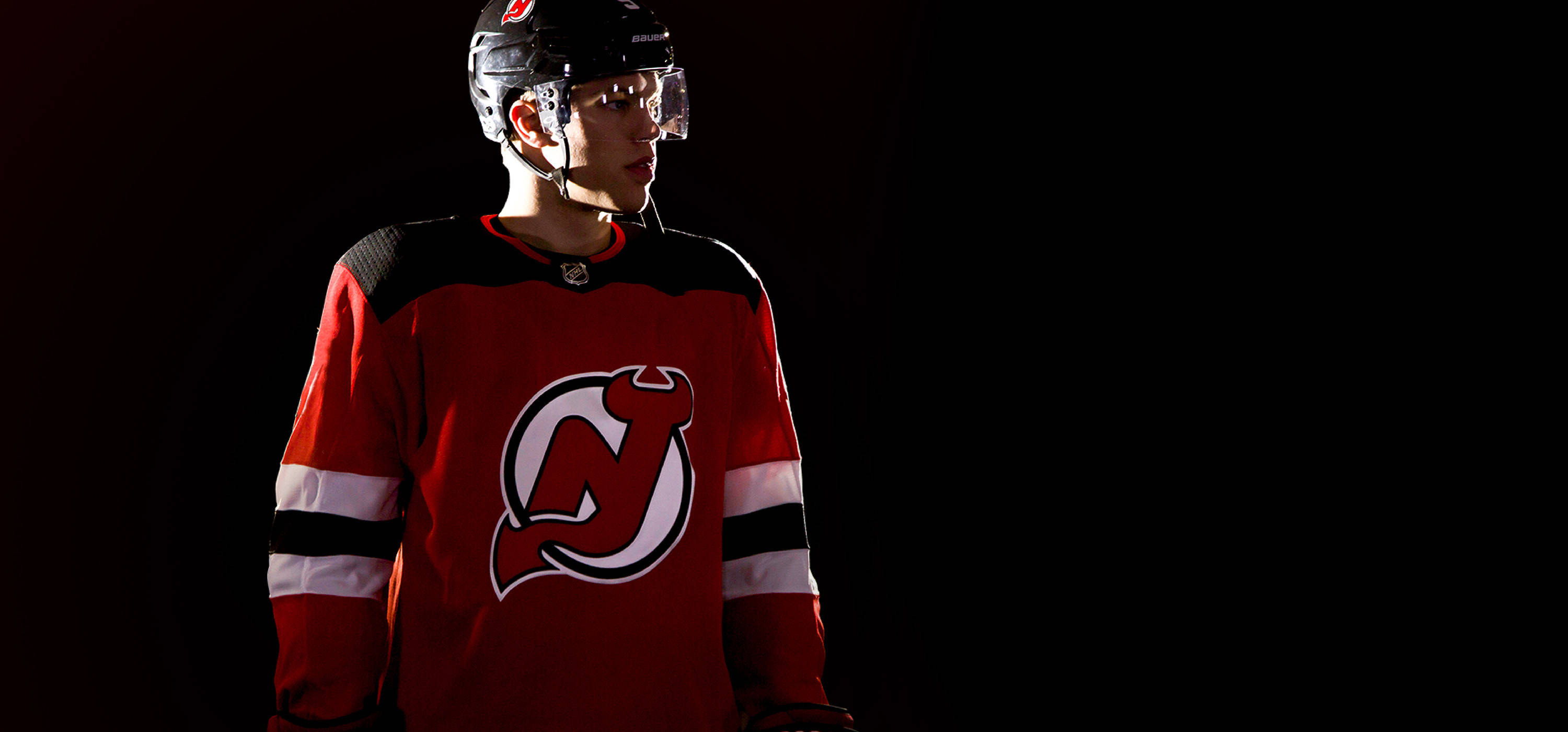 New 桌布 壁紙 — 一名身穿紅色紐澤西惡魔隊球衣的冰球運動員，在黑色背景前處於戲劇性的攝影棚燈光下。