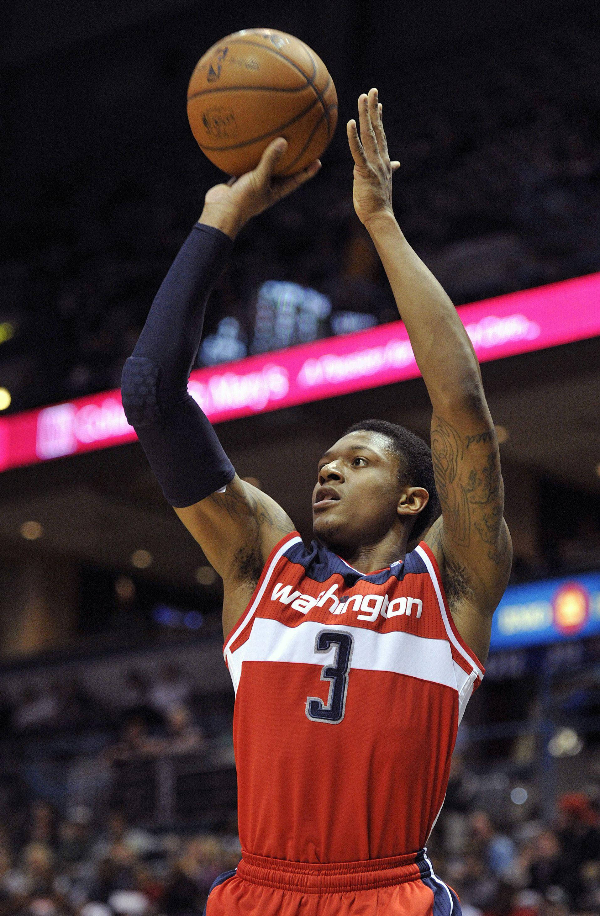 Bradley Beal 桌布 壁紙 — 一名身穿紅色華盛頓球衣的籃球運動員在場館燈光下專注地投出跳投。
