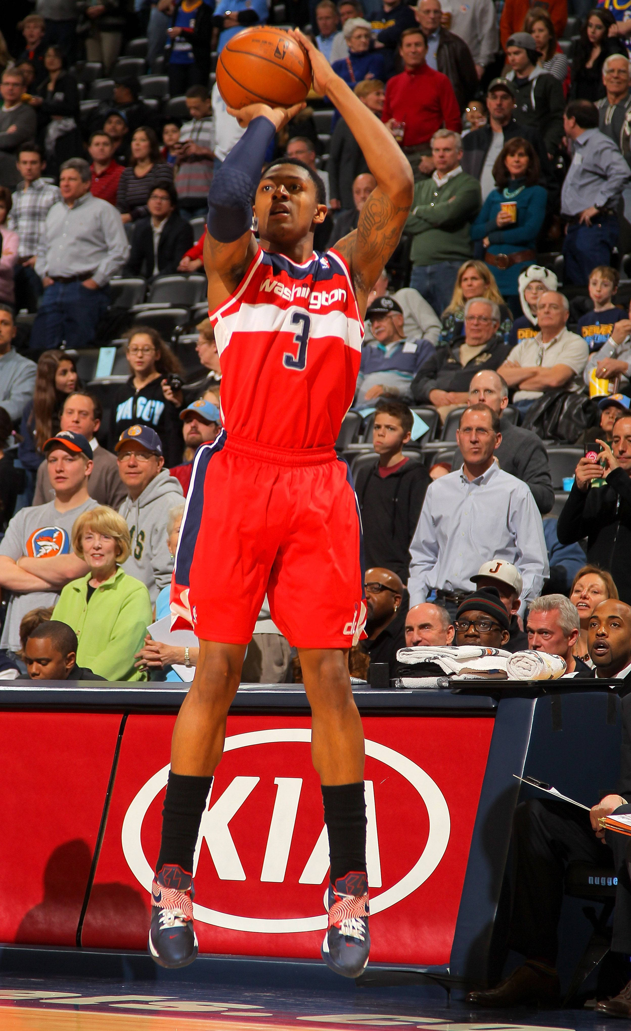 Bradley Beal 桌布 壁紙 — 一名身穿紅色華盛頓球衣的籃球運動員在比賽中跳起投籃，觀眾在觀看。