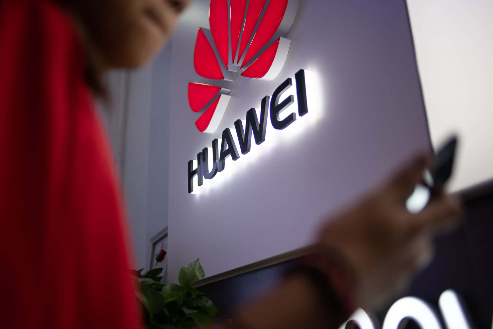 在Huawei標誌牌附近手持電話的人士（室內）