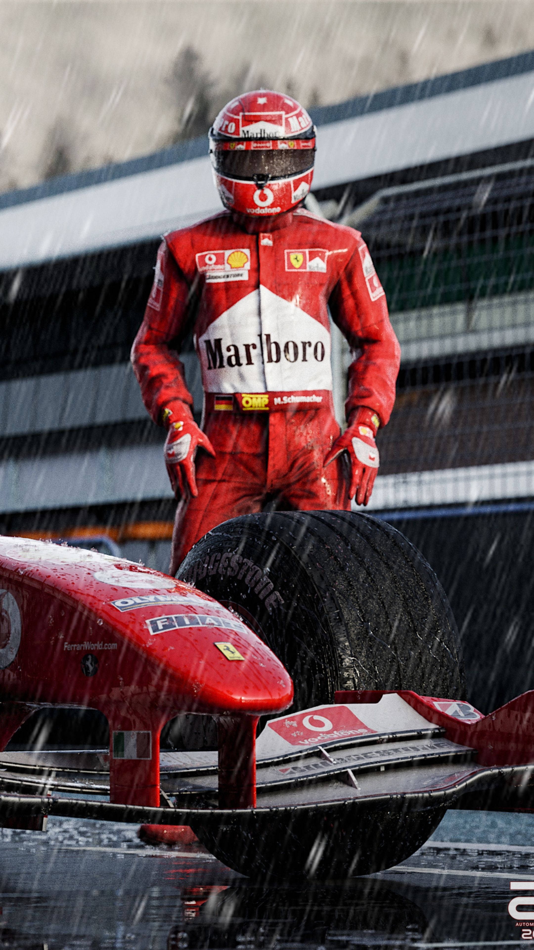 michael 桌布 壁紙 — 一名身穿紅色裝備的F1車手在暴雨中站在賽道上，旁邊是他濕透的紅色賽車。